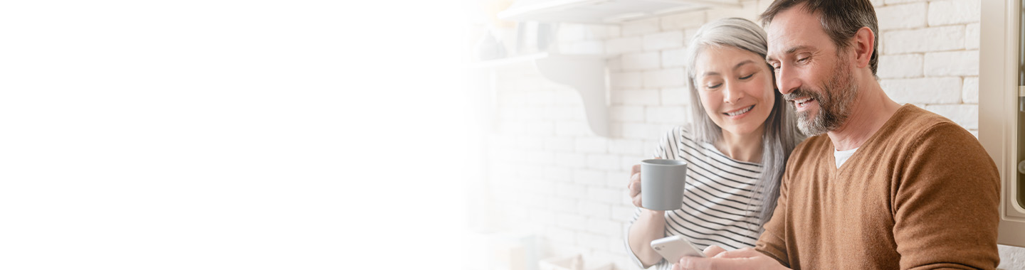 A couple having coffee and reading a phone together.