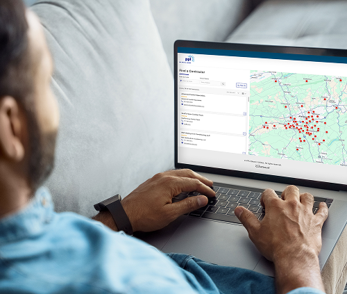 A person uses a laptop displaying the Find a Contractor tool with numerous red markers on a map. 