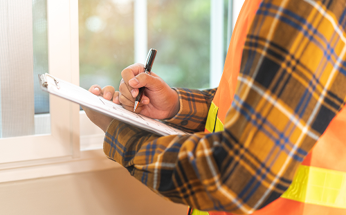 Contractor completing a home inspection and recording notes on a clipboard during a service visit.