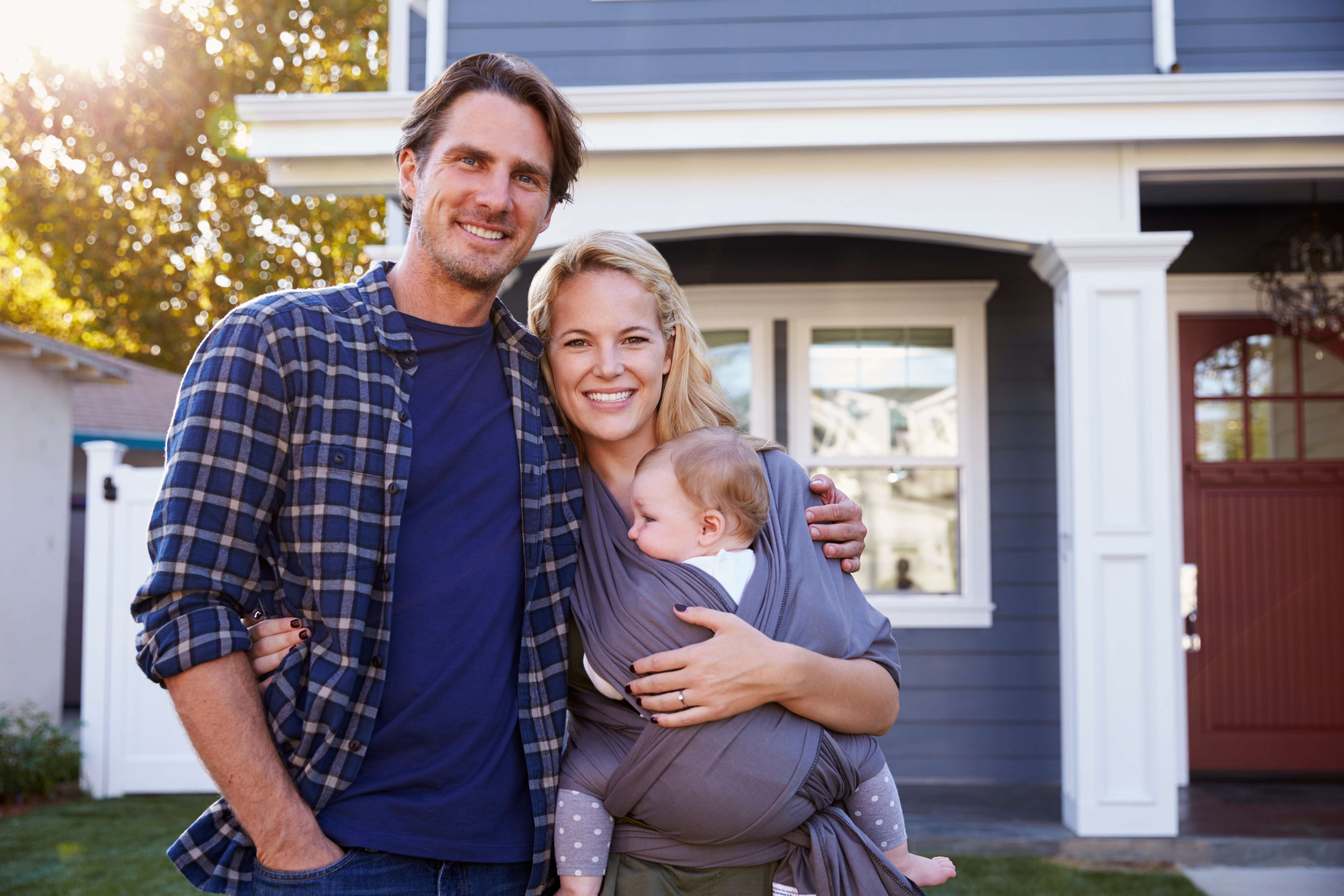 Family smiling standing in front of their home.